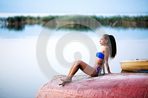 Girl on an upside down rowboat shot at sunset