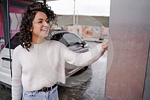 Girl use coin receptacle mounted on car wash