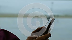 Girl uses phone in the airport lounge, the focus goes to the plane outside the window close-up