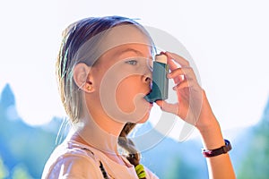 Girl using asthma inhaler in a park