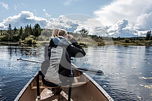 Girl using binocular on Canoe lake of two rivers in the algonquin national park in Ontario Canada on sunny cloudy day