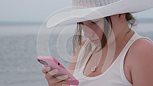 Girl using cellphone on a sea ocean shore. Young girl on the beach with your smartphone.