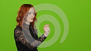 Girl using computer graphics virtually scrolls through photos. Green screen
