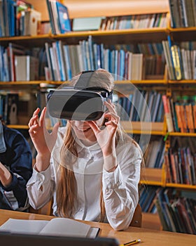 Girl using devices in the library, a laptop and VR headset