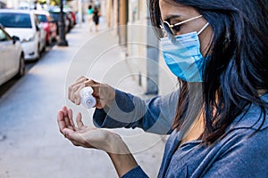 Girl using hand sanitizer wearing a mask