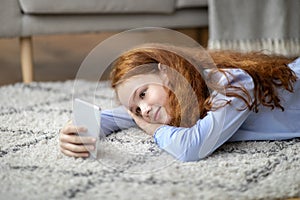 Girl using her cell phone lying on floor carpet