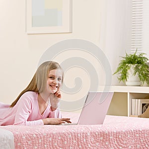 Girl using laptop for the internet in her bedroom