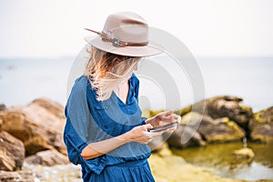 Girl using phone,Close up portrait of young woman in brown hat outdoor.having fun on the sea