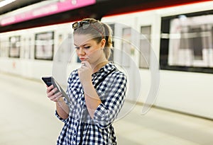 Girl using phone at metro station