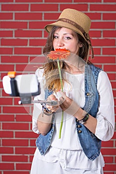 Girl using selfie stick in front of brick wall