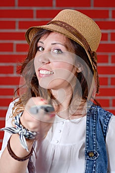 Girl using selfie stick in front of brick wall