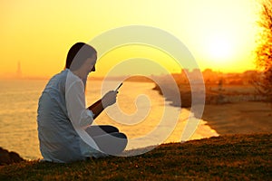 Girl using a smart phone in a beautiful sunset