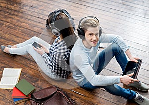 Girl using a smartphone and boy using a tablet in headphones listening to the music