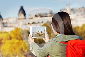 Girl using tablet making picture of autumn Paris