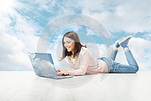 Girl using wireless laptop over sky background.