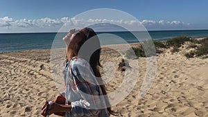 Girl vacationer enjoying summer heat on the beach and playing ukulele