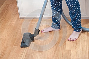 Girl vacuuming in room with vacuum cleaner at home. close up of woman legs with pedicure in home pants. housework concept