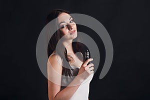 Young woman vaping e-cigarette on black