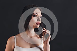 Young woman vaping e-cigarette on black