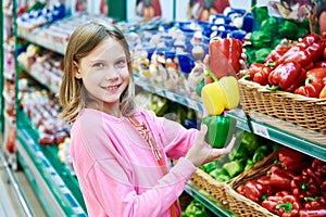 Girl with varicolored bell peppers in supermarket