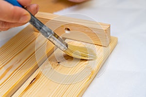 Girl varnishes a wooden detail.