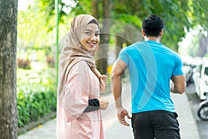 a girl in a veil smile looking at the camera when doing jogging together when outdoor exercise