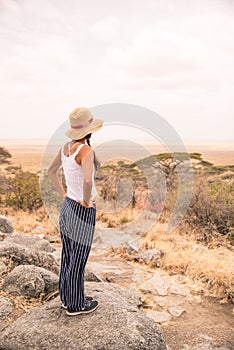 Girl at view point looking to the bush savannah of Serengeti at sunset, Tanzania - Safari in Africa