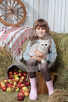 Girl villager with cat near pail, apples photo