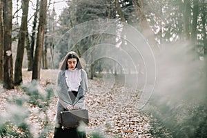 Girl with a vintage suitcase in the park. Beautiful dreamy girl portrait. Traveler with retro luggage. Romantic girl outdoors