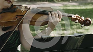 Girl violinist playing the violin outdoors.