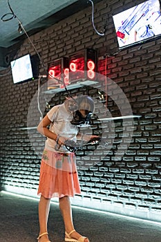 A girl in a virtual reality helmet with joysticks plays computer 3D games