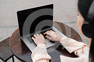 Girl with vitiligo skin pigmentation on the hands working on laptop online and listen music with headphones outdoor in