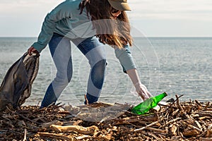 Girl volunteer helps clean the beach of debris. Earth day and environmental improvement concept