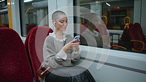 Girl voyager messaging smartphone sitting modern train. Short hair woman texting