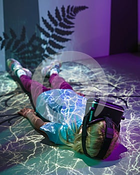 Girl with VR glasses laying on a floor, fluorescent light effects