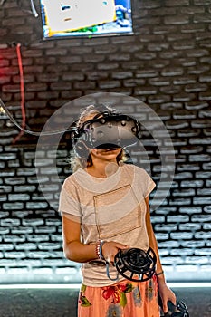 A girl in a VR helmet plays games in the computer room and controls joysticks