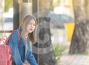 Girl wait for a bus.Bored teen waiting for parents outdoor on the metal bench sitting