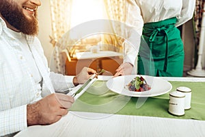 Girl waiter serves his dish in restaurant to a man