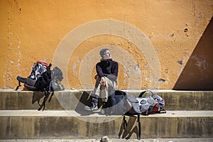 Girl waiting with backpacks in sun.