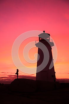 Girl waiting with flowers for her Valentine in the silhouette background of a lighthouse.