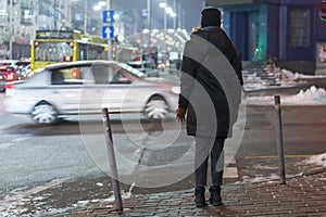 Girl waiting to cross the road while pedestrian traffic lights is red in the night city. close up