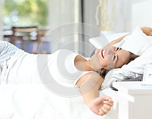Girl waking up stretching arms on the bed