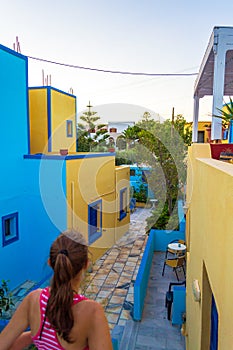 Girl on a walk alley between brightly painted traditional houses in Kamari Santorini