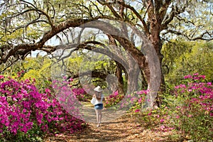 Girl walking alone in the beautiful blooming garden under oak trees.