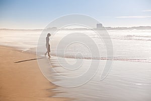 A girl is walking along the ocean