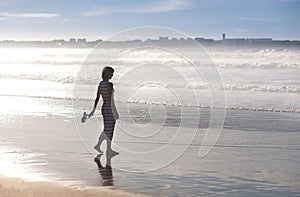A girl is walking along the ocean