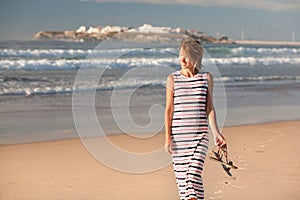 A girl is walking along the ocean