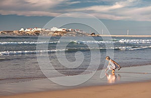 A girl is walking along the ocean