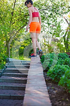 The girl is walking along the parapet.