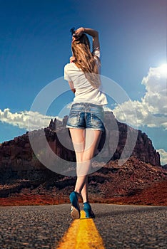 Girl walking along the road in the desert photo
